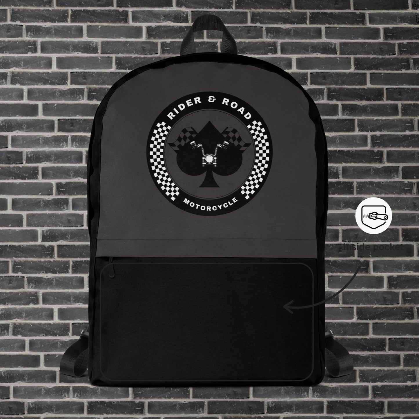 "Mochila color negro y gris oscuro con el el As de Picas y un manillar en su interior dentro de un circulo con el nombre "Rider & Road Motorcycle" - Black and dark grey backpack with the Ace of Spades and a handlebar inside a circle with the name ‘Rider & Road Motorcycle"