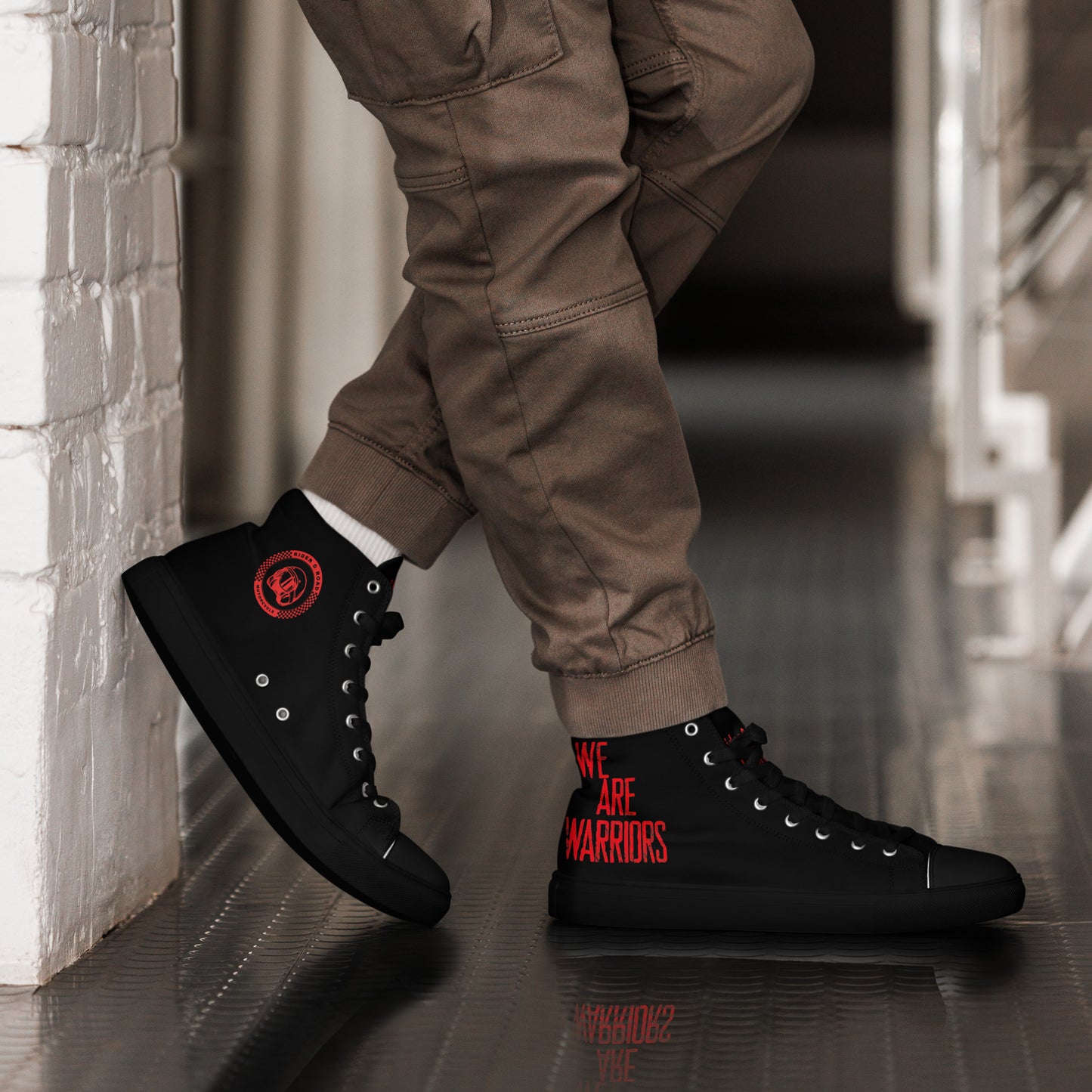"Zapatillas altas en cuero sintético negro con suela negra, suela gruesa y diseño agresivo para moteros y moteras, con palabras We Are Warriors en el lateral en rojo intenso - High-top trainers in black synthetic leather with black soles, thick soles and an aggressive design for motorcyclists, with the words “We Are Warriors” in bright red on the side"