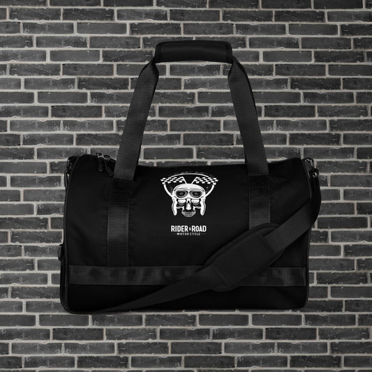 "Bolsa cilíndrica de 30 litros, color negro, con imagen estampada de una calavera con gorro de piloto de cuero y gafas, sobre la frase Rider&Road Motorcycle - 30-liter cylindrical bag, black, with a printed image of a skull wearing a leather pilot's cap and goggles, above the phrase Rider&Road Motorcycle"