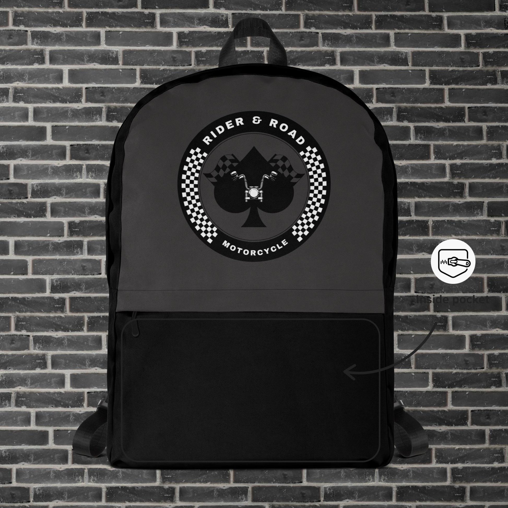 "Mochila color negro y gris oscuro con el el As de Picas y un manillar en su interior dentro de un circulo con el nombre "Rider & Road Motorcycle" - Black and dark grey backpack with the Ace of Spades and a handlebar inside a circle with the name ‘Rider & Road Motorcycle"