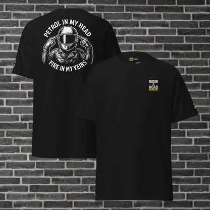 "Camiseta negra con estampado en la parte trasera en color blanco de un motero con los dedos apuntando a la cabeza y la frase petrol in my head, fire in my veins, tiene bordado el logo de Rider&Road en el pecho y en la manga izquierda - Black T-shirt with a white print on the back of a biker with his fingers pointing to his head and the phrase ‘petrol in my head, fire in my veins’. It has the Rider&Road logo embroidered on the chest and left sleeve"